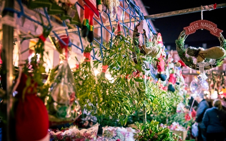 Weihnachtsmarkt auf Madeira mit festlich dekorierten St&auml;nden, Mistelzweigen und traditionellen Handwerkskunst, umgeben von stimmungsvollen Lichtern und fr&ouml;hlicher Atmosph&auml;re.