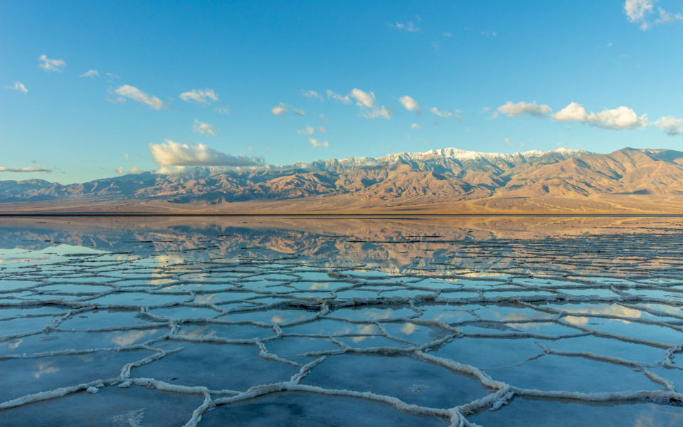 Salzformationen im Badwater Basin im Death Valley spiegeln sich in einer d&uuml;nnen Wasserschicht.